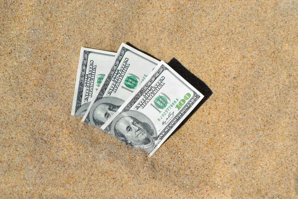 Geld dolars half bedekt met zand liggen op strand close-up — Stockfoto