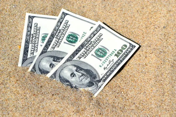 Geld dolars half bedekt met zand liggen op strand close-up. — Stockfoto