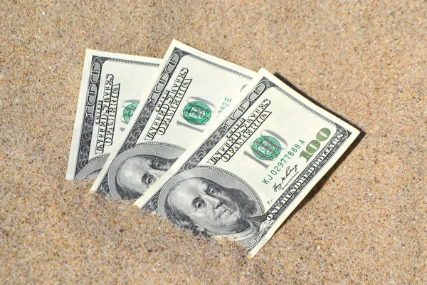 Geld dolars half bedekt met zand liggen op strand close-up. — Stockfoto