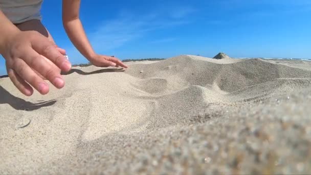 Movimento lento. Baixo ângulo. Menina pega um punhado de areia na palma da mão — Vídeo de Stock