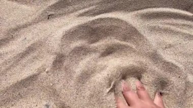 İnsanlar elleriyle parmaklarından kum saçıyor..