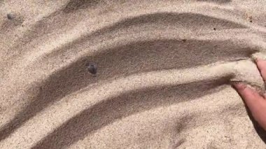 İnsanlar elleriyle parmaklarından kum saçıyor..