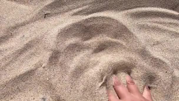 Мужская рука рассеивает песок сквозь пальцы. . — стоковое видео