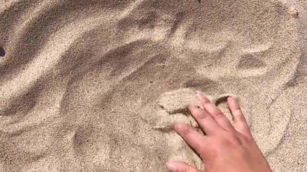 Mans hand scatters sand through his fingers. — Stock Video