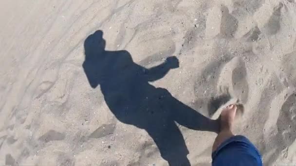 Черная тень девушки, идущей вдоль песчаного пляжа на берегу — стоковое видео