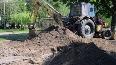Traktör toprağı kazıyor. Kepçeler yere yakın çekim yapıyor..