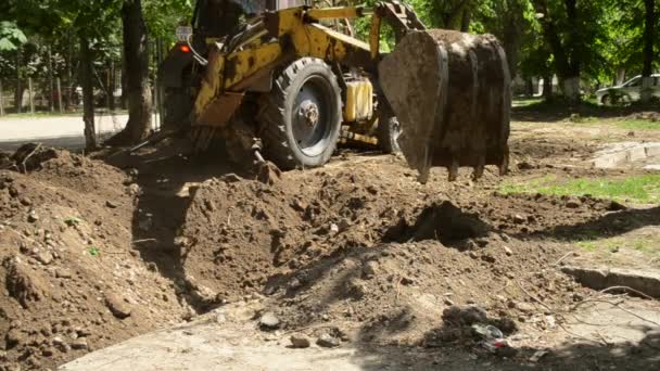 Tractor pits the ground. Backhoe piles up the ground close-up. — Stock Footage Tractor pits the ground. Backhoe piles up the ground close-up. Stock Footage