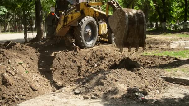 Tractor slaat de grond in. Backhoe stapelt de grond op close-up. — Stockvideo