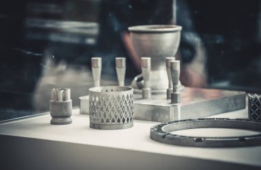 Metal 3D yazıcıya yazdırılmış nesneyi tutan adam.