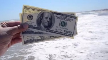 Man holds three hundred dollar banknotes in his hands on a background
