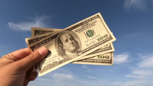 Girl holding money bill of 300 dollars on background of blue sky — Stockvideo