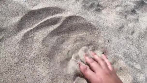 Мужская рука рассеивает песок сквозь пальцы. Движение рук — стоковое видео