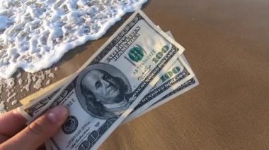 Man holds three hundred dollar banknotes in his hands on the background