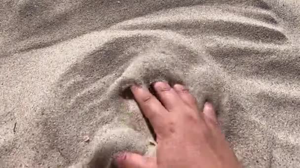 Мужская рука рассеивает песок сквозь пальцы. Движение рук — стоковое видео
