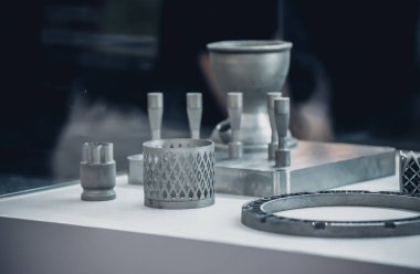 Metal 3D yazıcıya yazdırılmış nesneyi tutan adam.