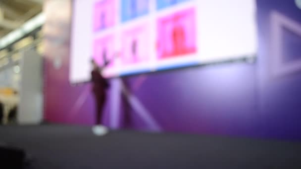 Man stands on stage. Blurred background large screen stage many people — 图库视频影像