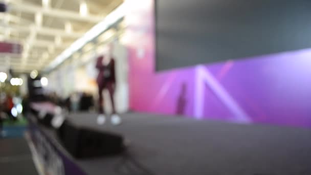 Man stands on stage. Blurred background large screen stage many people — 图库视频影像