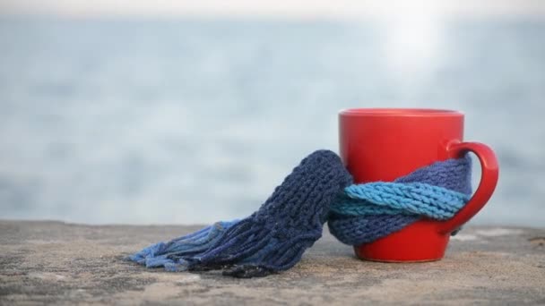 Tazza rossa con caffè caldo e tè al vapore, legata con sciarpa blu a maglia — Video Stock