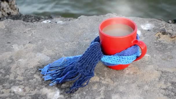Xícara vermelha com chá de café quente e vapor, amarrado com cachecol de malha azul — Vídeo de Stock