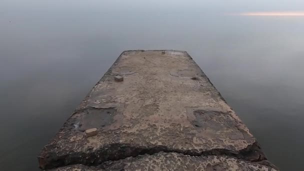 Camminando su un molo di pietra di cemento sulla riva del mare — Video Stock