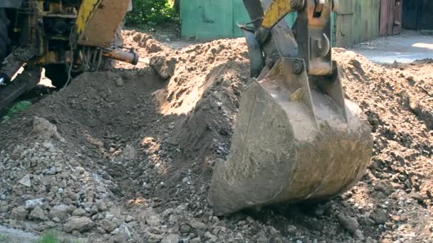 Backhoe stapelt de grond van dichtbij op. Oude trekker bij onderhoudswerkzaamheden. — Stockvideo