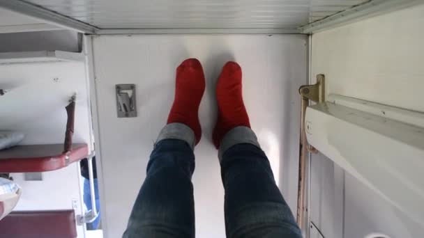 Girl lies on the side bed in the reserved seat of the train car and put her legs — Stock Video