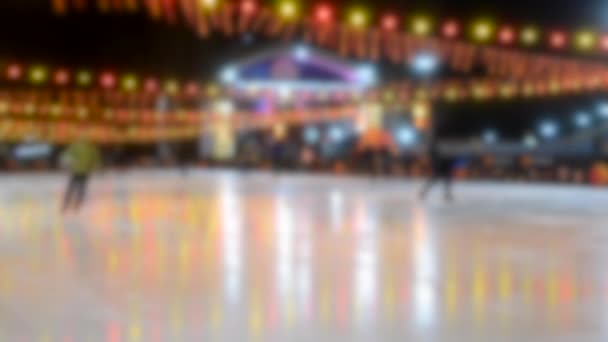 Les gens roulent sur une patinoire avec une lampe à guirlande jaune-rouge lumineuse . — Video