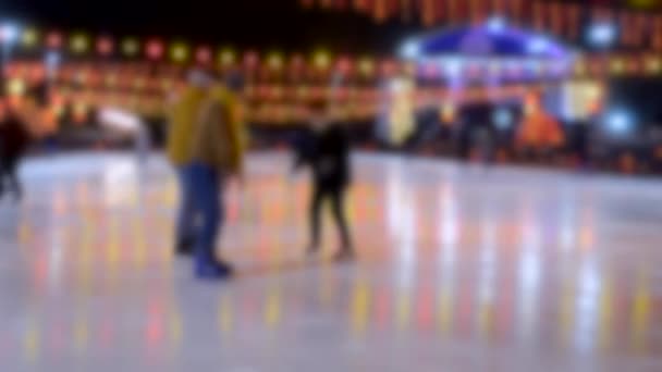 Les gens roulent sur une patinoire avec une lampe à guirlande jaune-rouge lumineuse . — Video