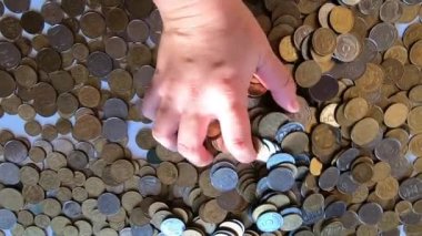 Kız eline bir avuç bozuk para alıp masanın üstüne fırlatıyor.
