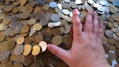 Kız eline bir avuç bozuk para alıp masanın üstüne fırlatıyor.
