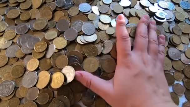 Mädchen nimmt eine Handvoll Münzen in die Hand und wirft sie über Münzen auf den Tisch — Stockvideo