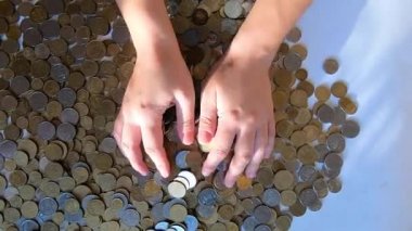 İki el masaya bozuk para döker ve avuçtan yüzeye dökülür.