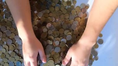 İki el masaya bozuk para döker ve avuçtan yüzeye dökülür.