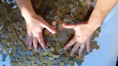 İki el masaya bozuk para döker ve avuçtan yüzeye dökülür.