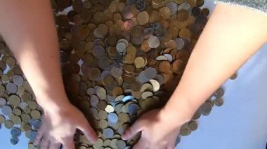 İki el masaya bozuk para döker ve avuçtan yüzeye dökülür.