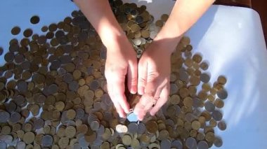 İki el masaya bozuk para döker ve avuçtan yüzeye dökülür.