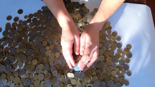 Pessoa duas mãos ancinhos moedas na mesa e derrama derramamentos de punhado para a superfície — Vídeo de Stock