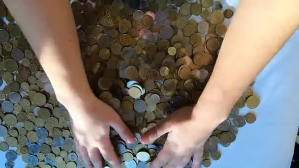 Человек две руки грабли монеты на стол и разливает от горстки к поверхности — стоковое видео