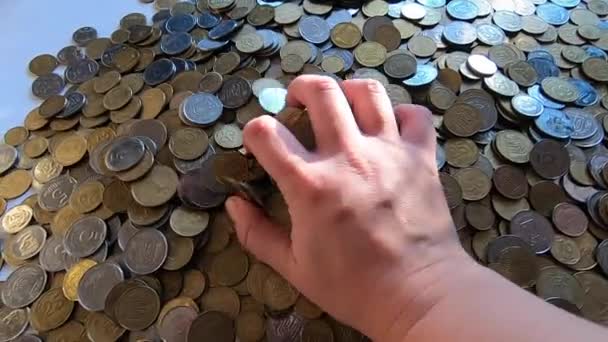Girl picks up handful of coins in her hand and throws it over coins on table — Stock Video
