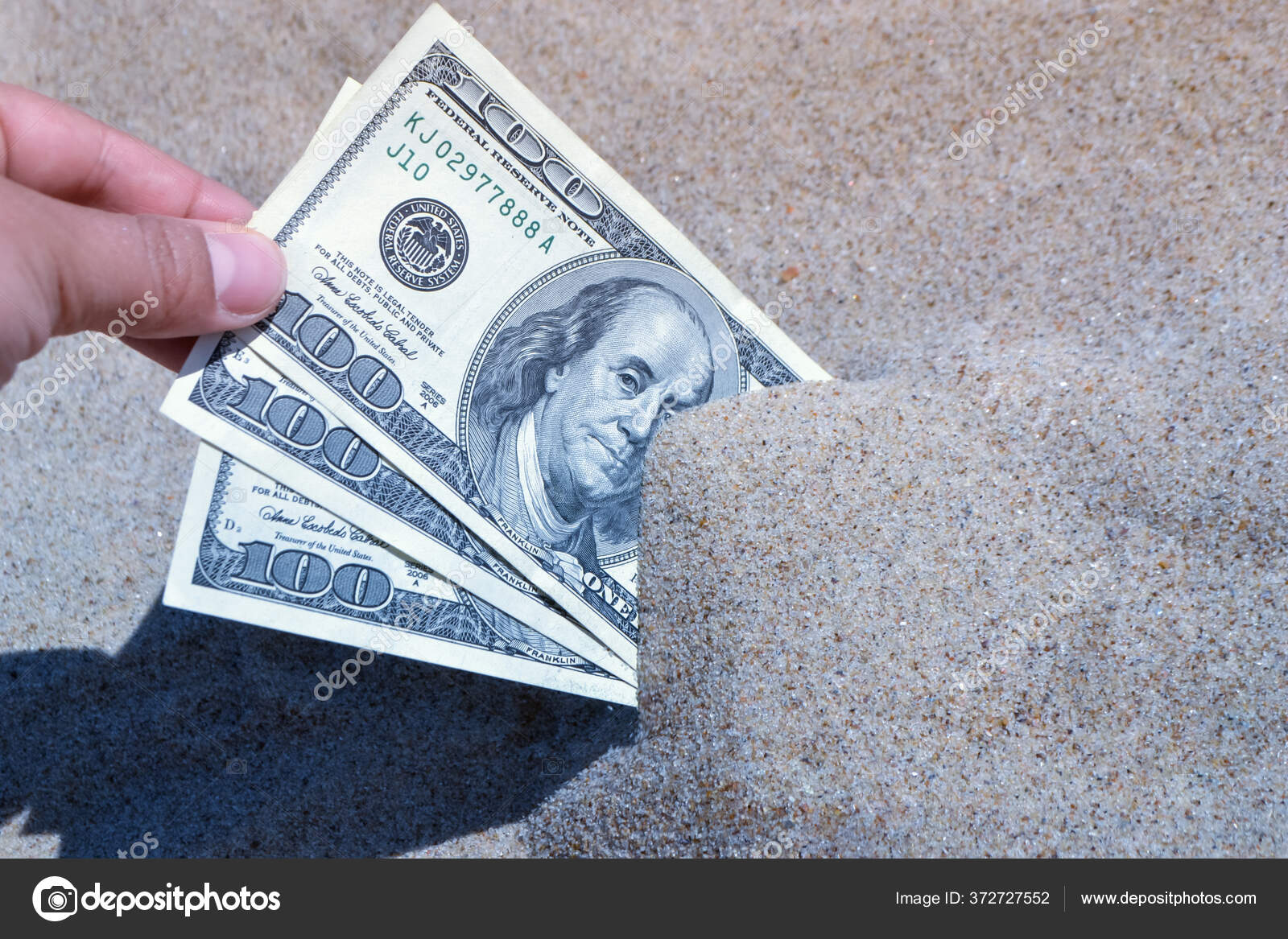 A girl takes out from the sand money notes of three hundred dollars