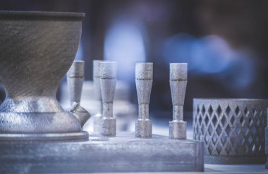 Metal 3D yazıcıya yazdırılmış nesneyi tutan adam.