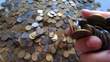 Eline bir avuç bozuk para alır ve masanın üstüne atar..
