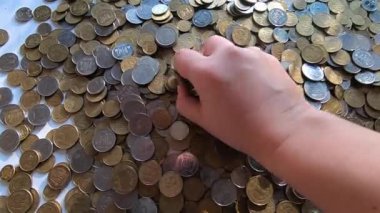 Eline bir avuç bozuk para alır ve masanın üstüne atar..