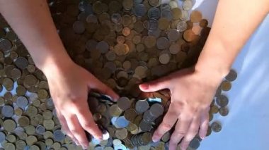 İki el masaya bozuk para döker, avuçtan yüzeye dökülür.