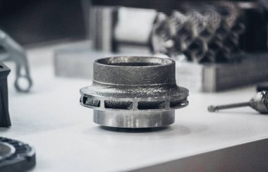 Metal 3D yazıcıya yazdırılmış nesneyi tutan adam