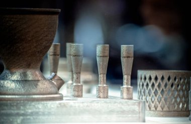 Metal 3D yazıcıya yazdırılmış nesneyi tutan adam.