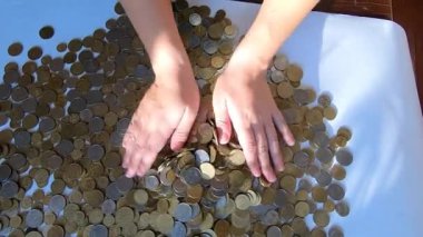 İki el masaya bozuk para döker ve avuçtan yüzeye dökülür.