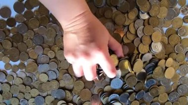 Kız eline bir avuç bozuk para alıp masanın üstüne fırlatıyor.