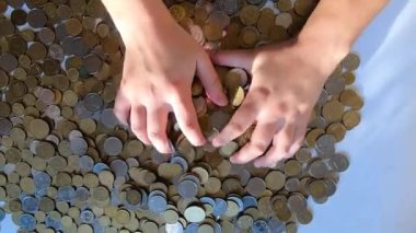 İki el masaya bozuk para döker ve avuçtan yüzeye dökülür.