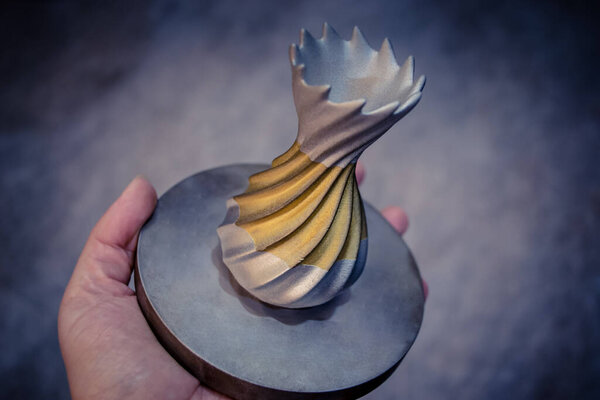 Человек держит объект, напечатанный на металлическом 3D принтере. Объект, отпечатанный в машине лазерного спекания. Современная 3D печать принтера из металлического порошка. Технология прогрессивной аддитивной печати DMLS, SLM, SLS 3d